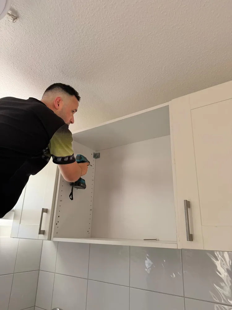 Mitarbeiter montiert einen Hängeschrank in der Küche