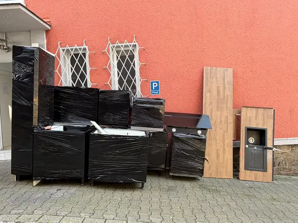 In schwarze Folie verpackte Küchenteile vor einem Wohnhaus