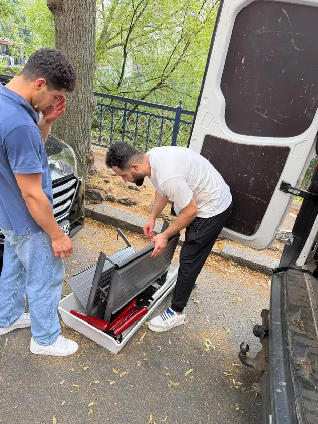 Mitarbeiter baut ein Möbelstück vor dem Transporter zusammen
