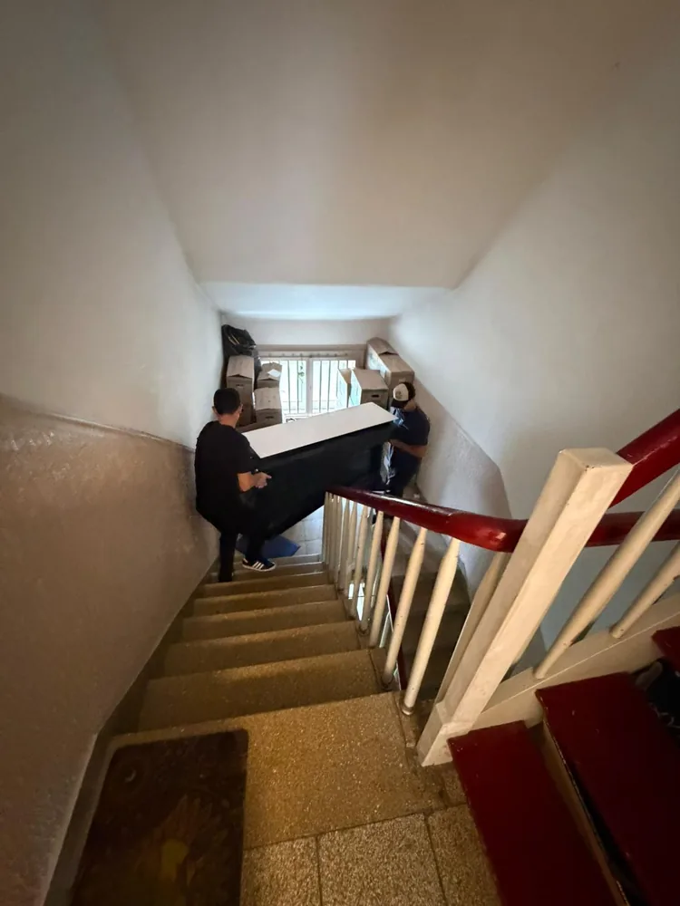 Mitarbeiter trägt ein Möbelteil durch ein enges Treppenhaus