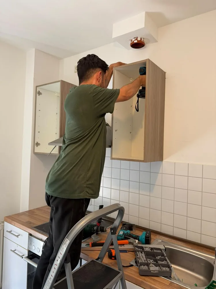 Mitarbeiter montiert einen Wandschrank über der Küchenzeile